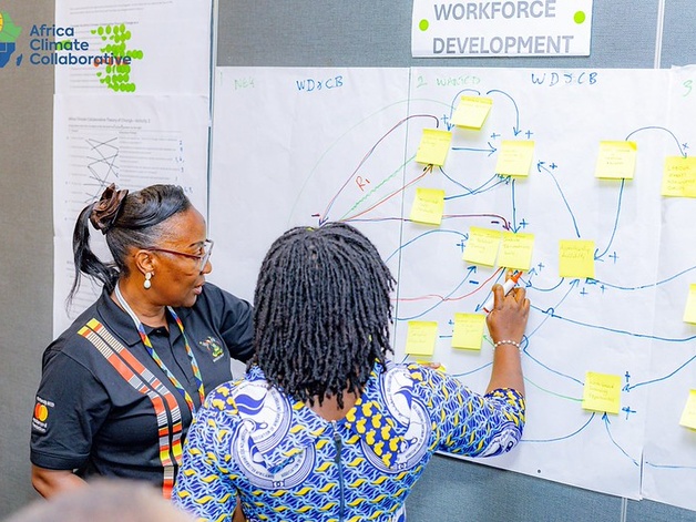 Two women adding sticky notes to a flipchart